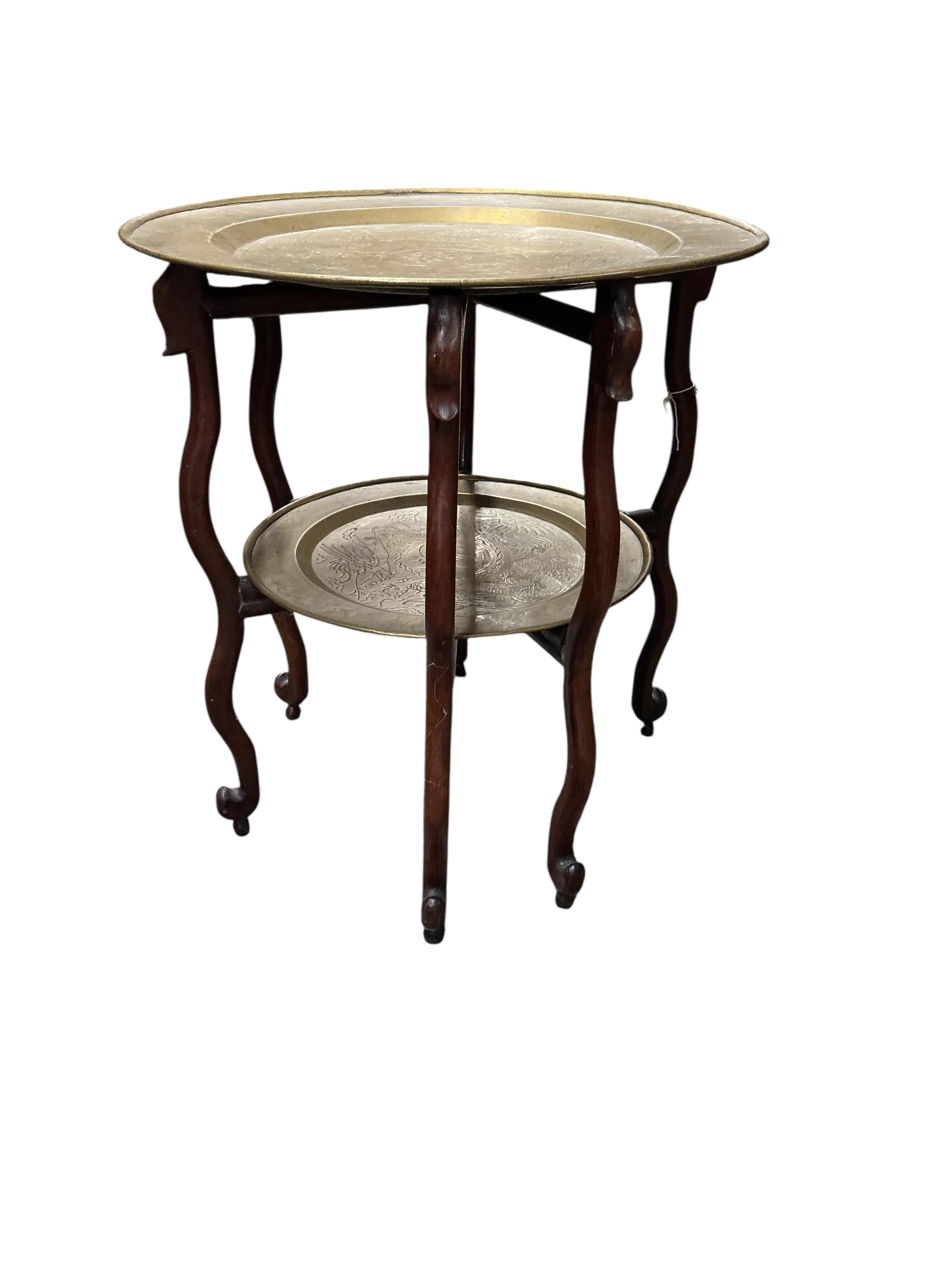 An early 20th century Chinese circular brass and hardwood two tier folding tea table, diameter 56cm, height 62cm